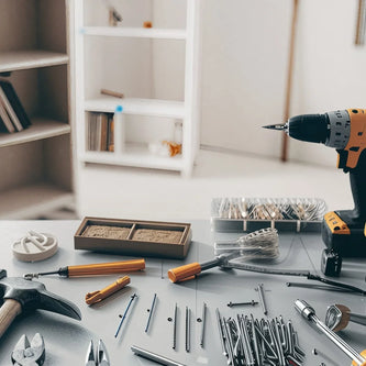 Assorted DIY home improvement tools and accessories arranged on a grey work table.