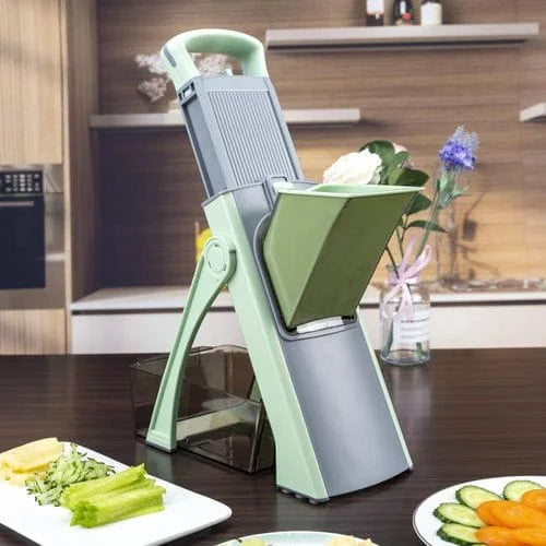 Green and gray vegetable chopper on a kitchen counter with plates of chopped vegetables.