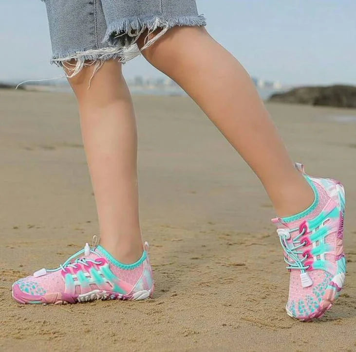 Pink and blue water shoes worn on a sandy beach