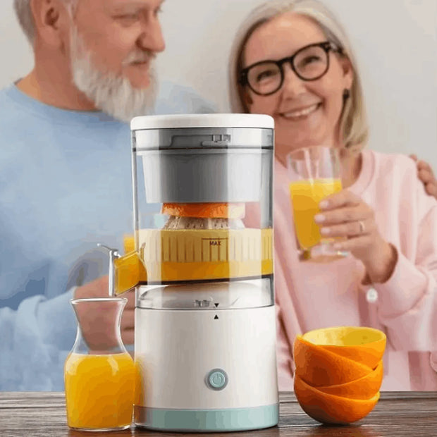 Juicer with oranges and glasses of juice on a table, with a blurred background of two people.