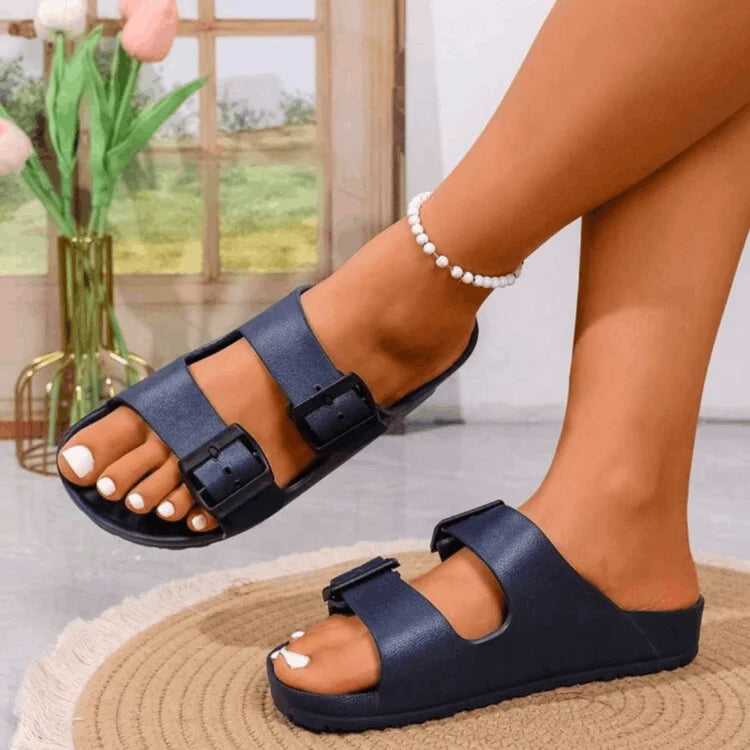 Navy blue sandals worn by a person indoors with a blurred background