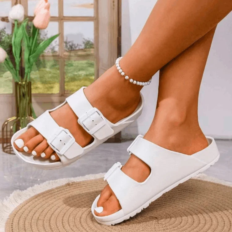 White sandals worn by a person indoors with a blurred background