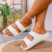 White sandals worn by a person indoors with a blurred background