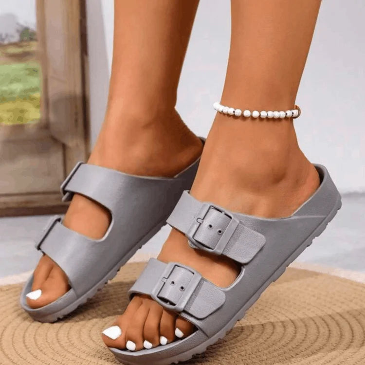 Gray sandals worn on feet with a blurred background