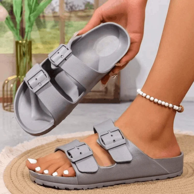 Gray sandals with buckle straps worn by a person indoors.
