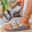 Gray sandals with buckle straps worn by a person indoors.