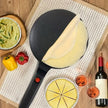 Cooking pan with folded omelette, vegetables, and wine on a wooden table