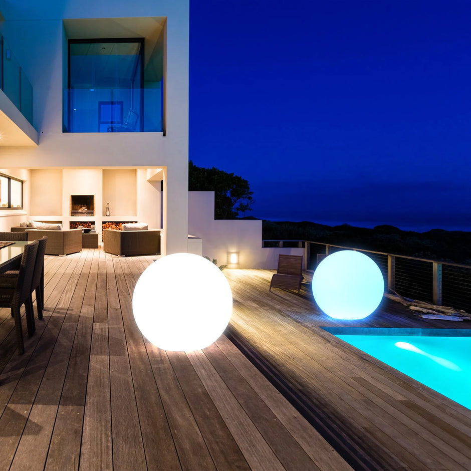 Modern outdoor setting with illuminated spherical lights near a pool at night.
