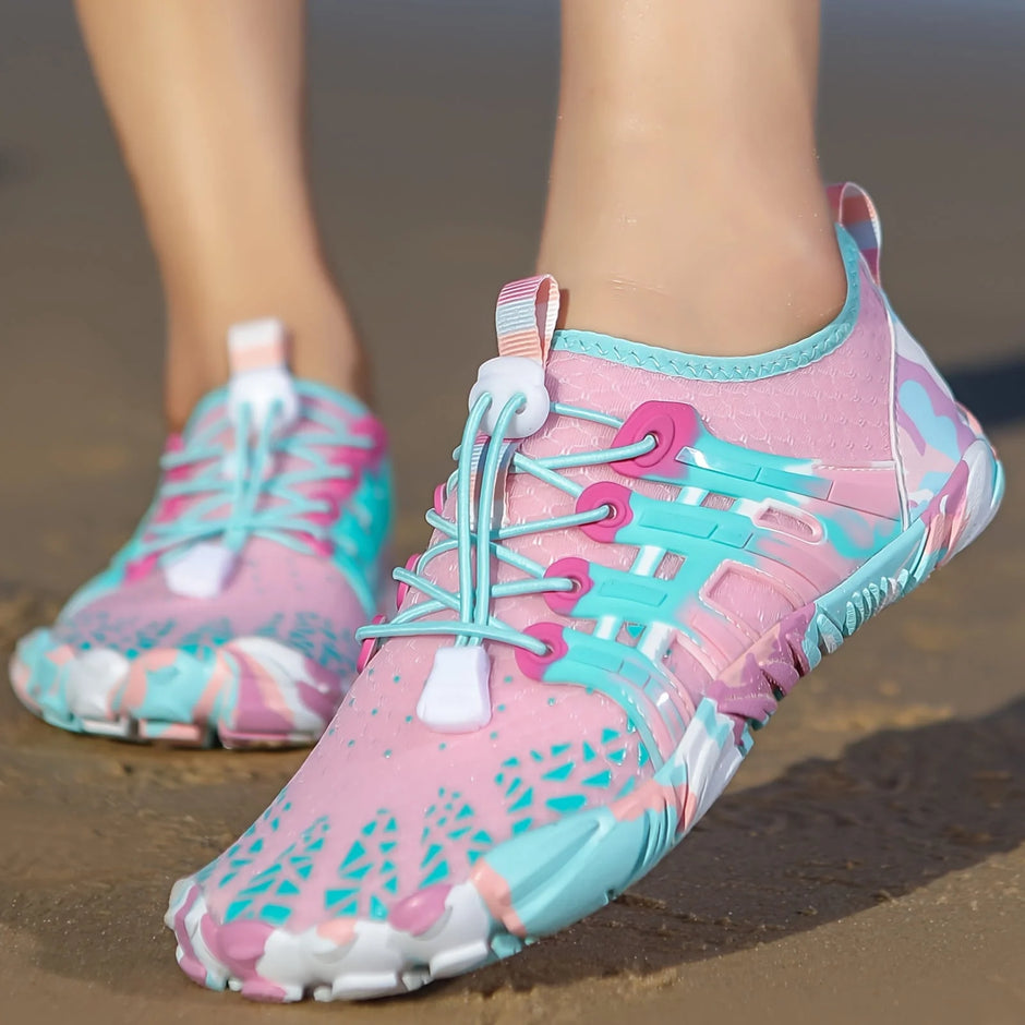 Pink and blue athletic shoes on a sandy surface