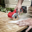 Person using a cordless circular saw to cut wood outdoors