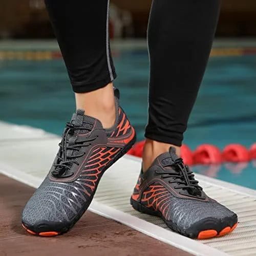 Person wearing black and orange athletic shoes by a pool.
