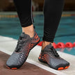 Person wearing black and orange athletic shoes by a pool.