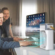 Two people working at a desk with a computer and a white air purifier.
