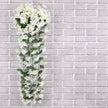 Artificial white flower vine against a gray brick wall