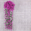 Artificial purple flowering vine against a gray brick wall
