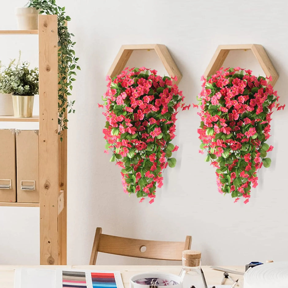 Hexagonal wall planters with pink flowers on a white wall next to a wooden shelf.