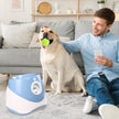 Man sitting on a couch with a dog holding a tennis ball, next to a pet water fountain.