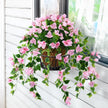 Artificial pink flowering plant in a pot on a windowsill.