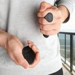 Person holding two black electronic devices with textured surfaces.