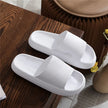 White slippers on a wooden surface with a vase in the background