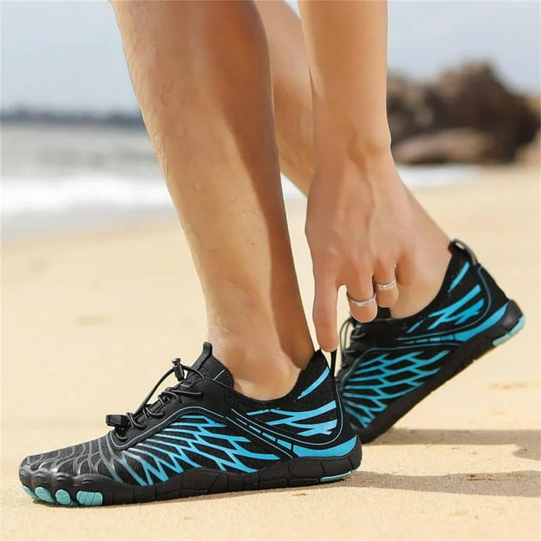 Person wearing black and blue patterned shoes on a beach.