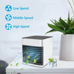 Portable air cooler on a table with a plant and decorative items, featuring speed settings.