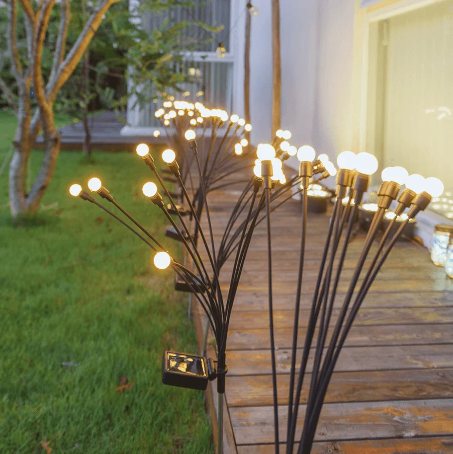Decorative outdoor lights on a garden path with a house in the background