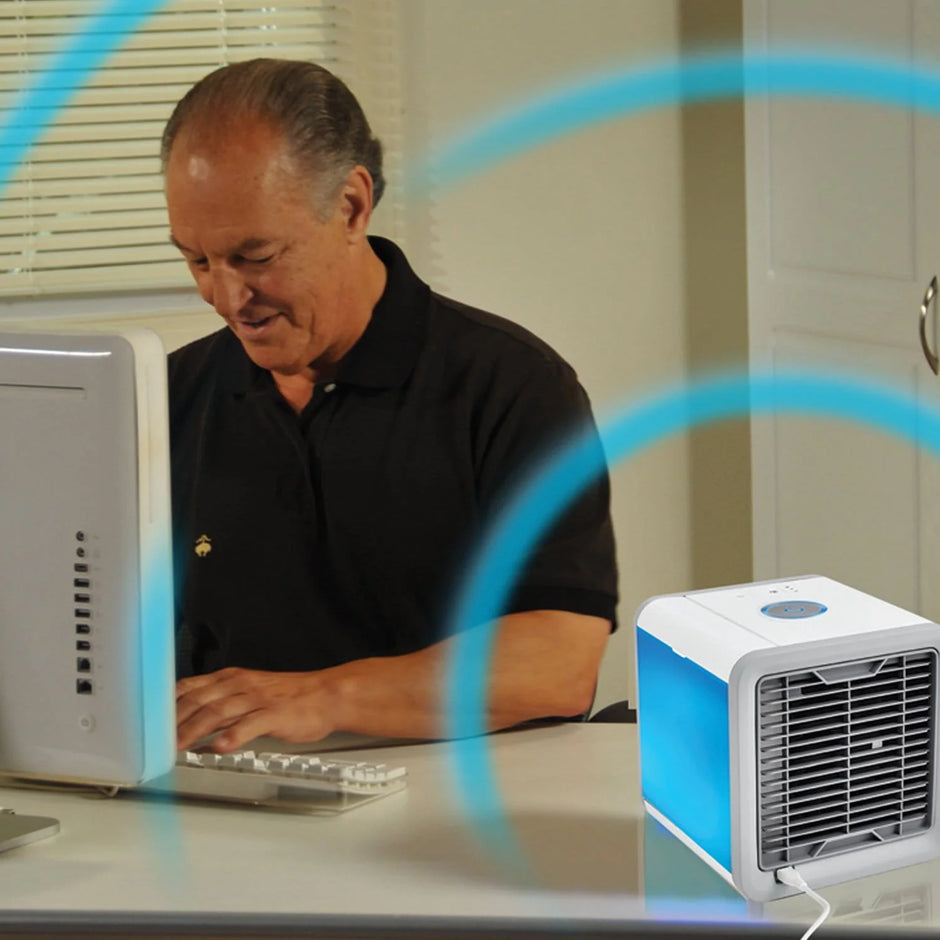 Man using a computer with a small air conditioner on the desk