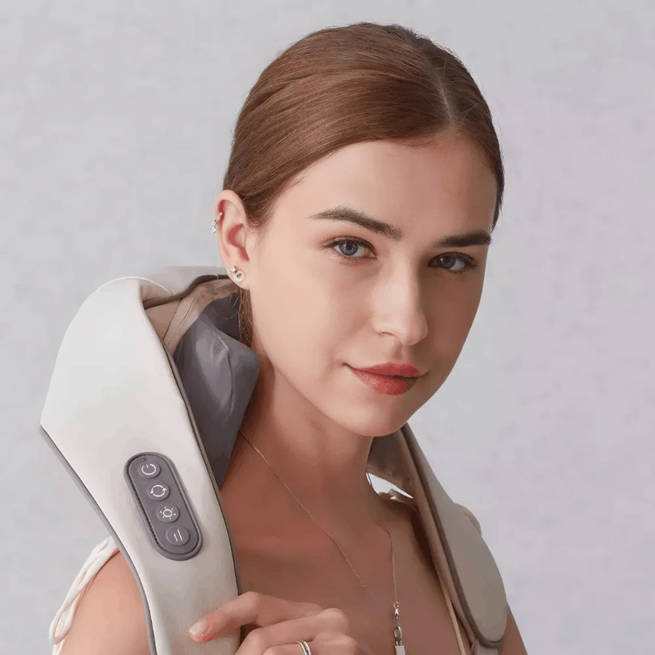 Woman using a white neck and shoulder massager against a light gray background