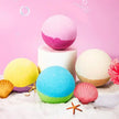 Colorful bath bombs with shells and starfish on a pink background