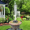 Decorative garden fountain with solar panel and bird statues in a lush green garden.