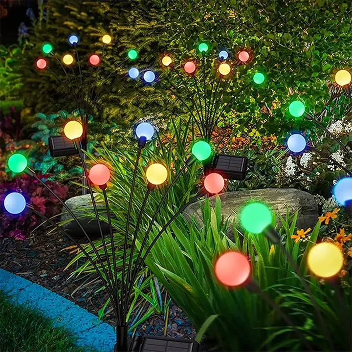 Colorful string lights with solar panels on plants in a garden setting
