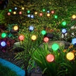 Colorful string lights with solar panels on plants in a garden setting