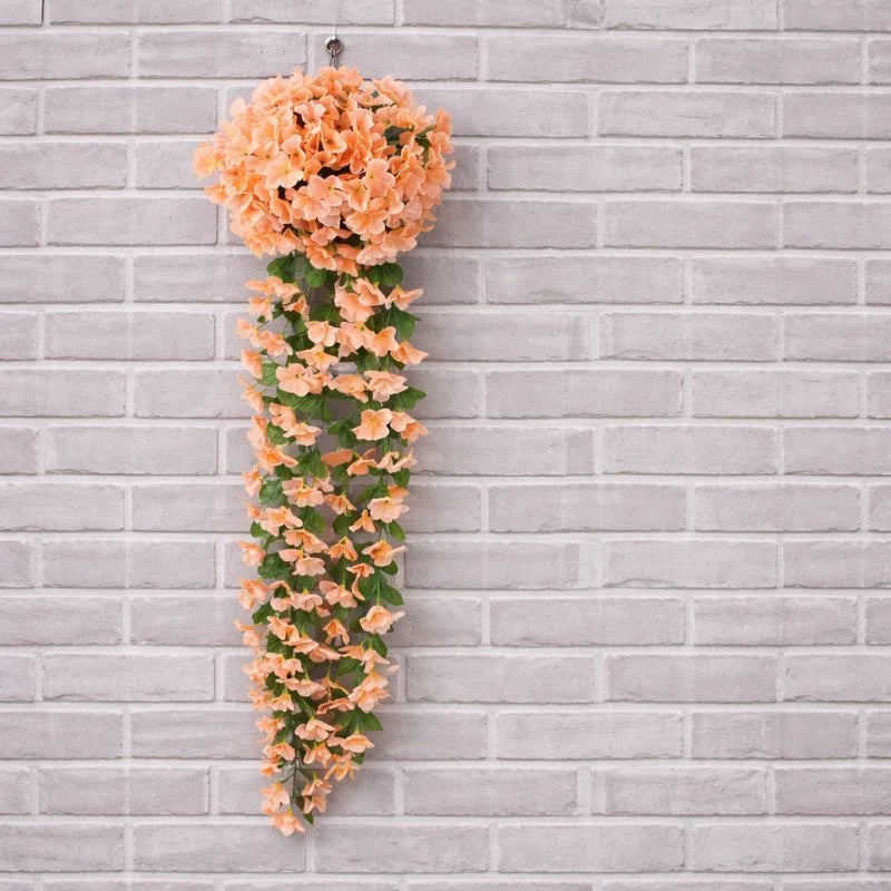 Artificial peach-colored floral garland against a gray brick wall