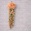 Artificial peach-colored floral garland against a gray brick wall