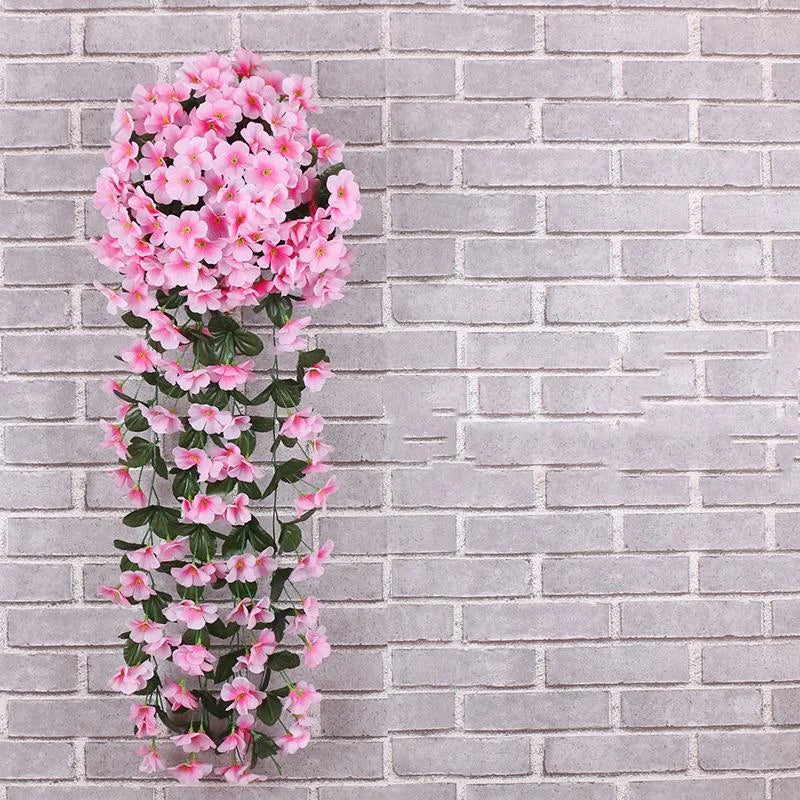 Artificial pink flowering vine against a gray brick wall