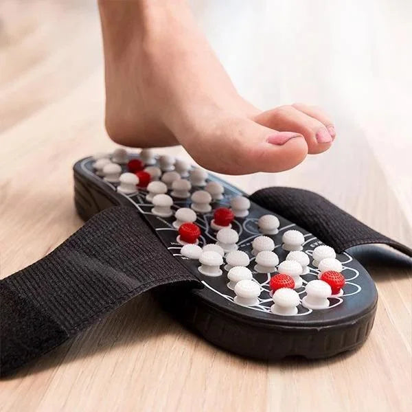 Foot wearing a massage insole with acupressure nodes on a wooden floor.