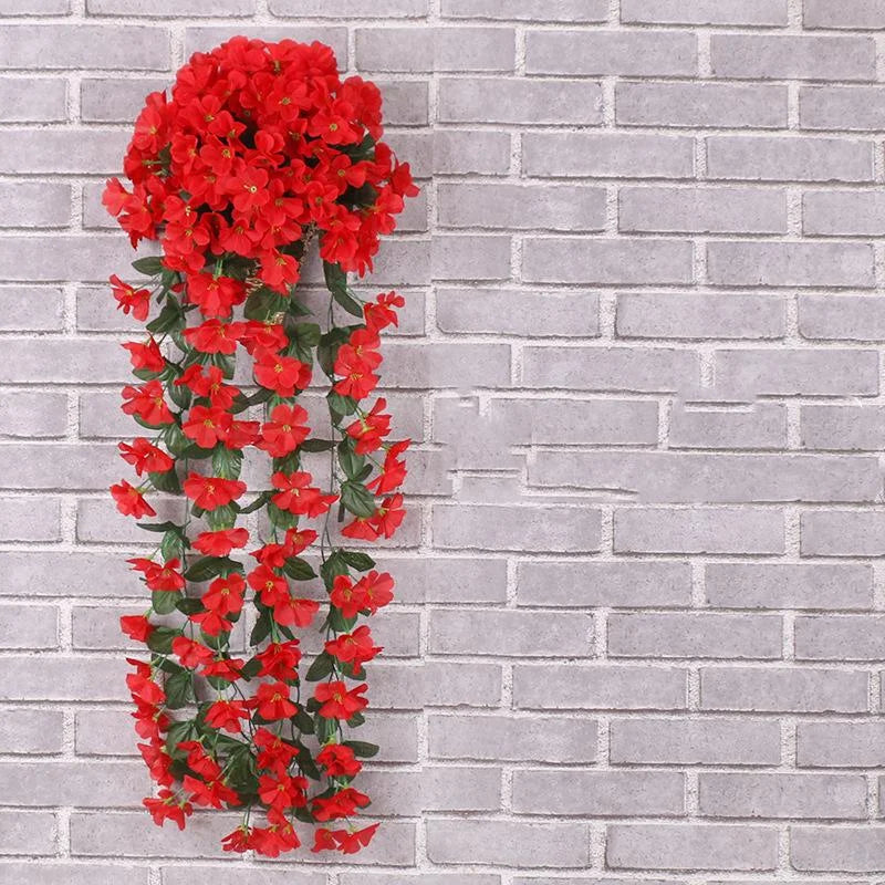 Red artificial flower garland against a gray brick wall