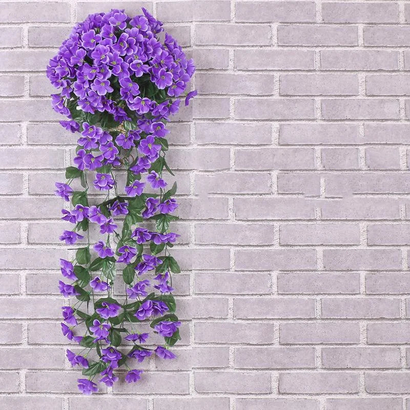 Artificial purple flower vine against a gray brick wall