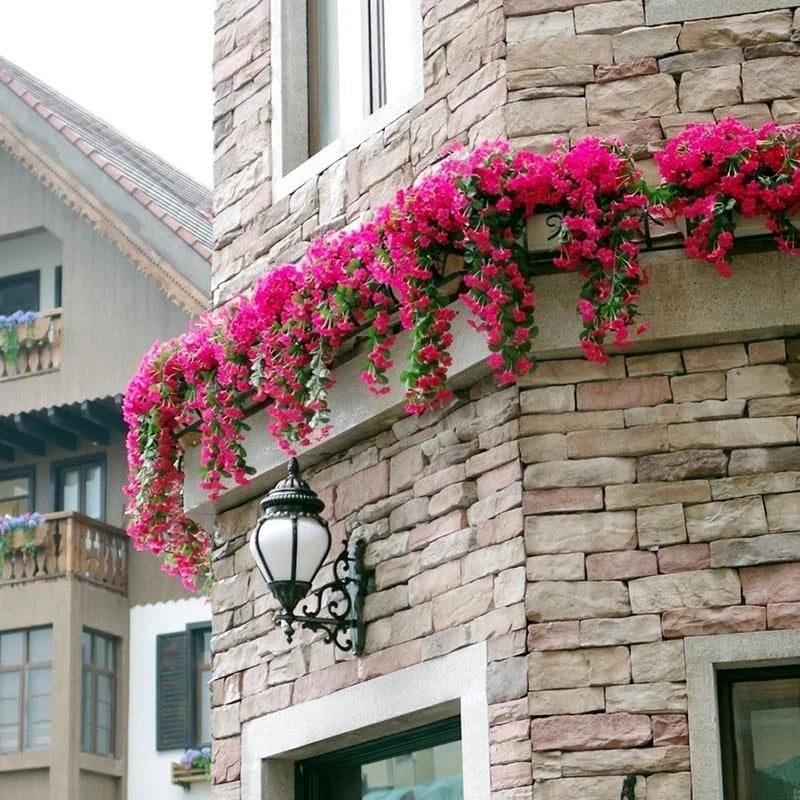Floral arrangement on a stone building facade with a street lamp.