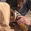 Person using a grinder on a piece of wood with a blurred background