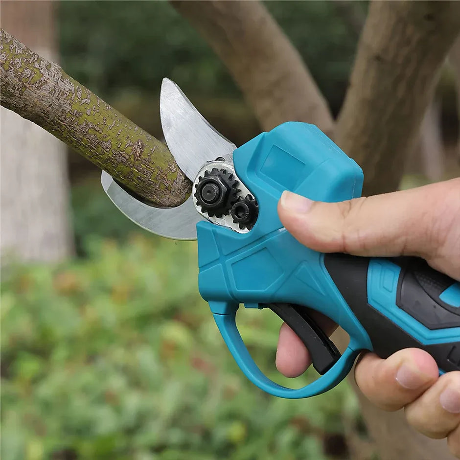 Electric pruning shears being used to trim a branch with a blurred natural background