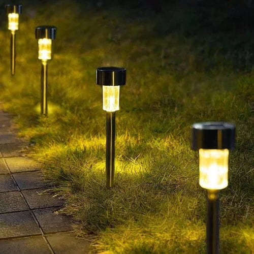 Solar pathway lights on grass next to a paved walkway