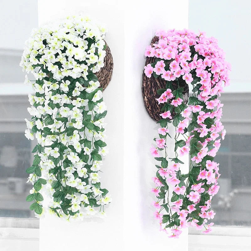 Two decorative wreaths with artificial flowers, one white and one pink, on a neutral background.