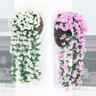 Two decorative wreaths with artificial flowers, one white and one pink, on a neutral background.
