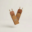 Pair of brown leather straps with gold hooks on a light beige background