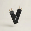 Black straps with gold hooks and a visible logo on a light beige background