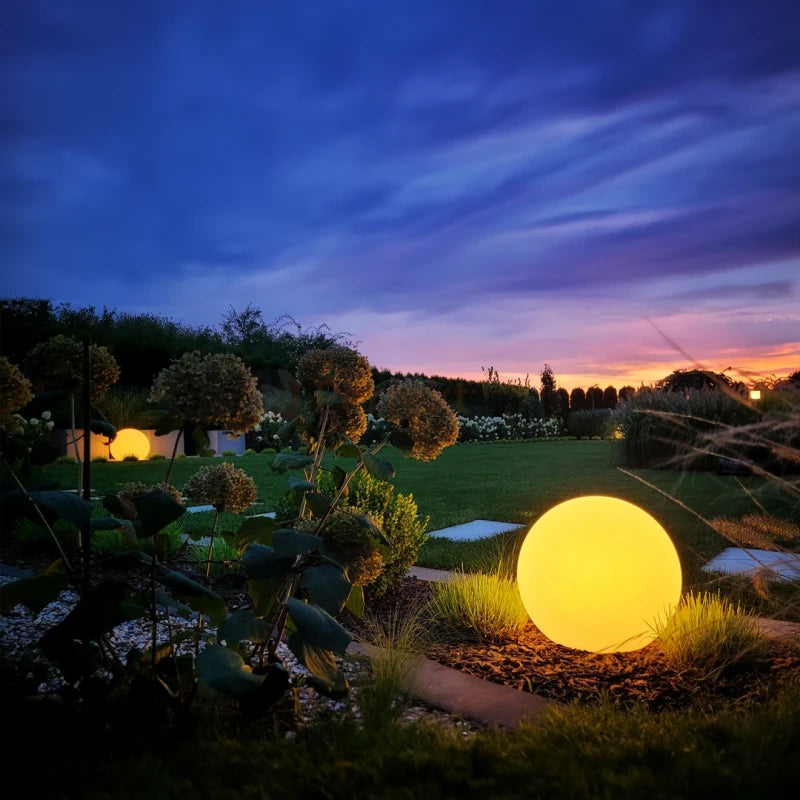 Glowing spherical light in a garden at night with a colorful sky.