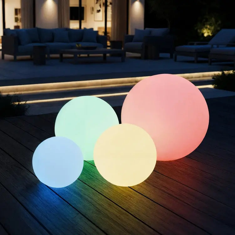 Four colorful LED balls on a wooden deck at night.