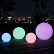 Four colorful LED balls on a wooden deck with a cityscape in the background.
